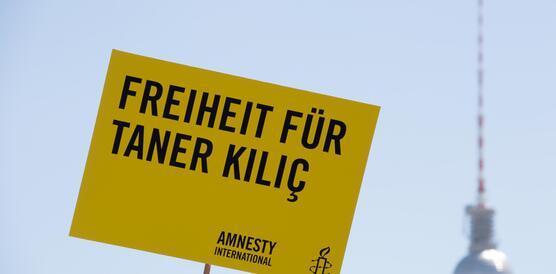 Ein Schild wird hochgehalten auf dem "Freiheit für Taner Kilic" steht