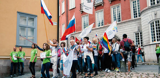 Eine Gruppe von Frauen und Männern mit verschiedenen Flaggen zieht durch eine Gasse in der Altstadt