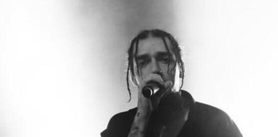 Mann steht mit dem Mikrofon auf der Bühne und singt