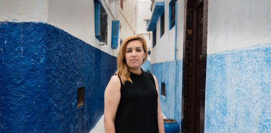 Porträtfoto von Nawal Benaissa zwischen blau-weiß gestrichenen Häusern