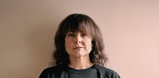 Porträtfoto einer Frau in schwarzem Pullover mit der Aufschrift Repeal vor einer weißen Wand