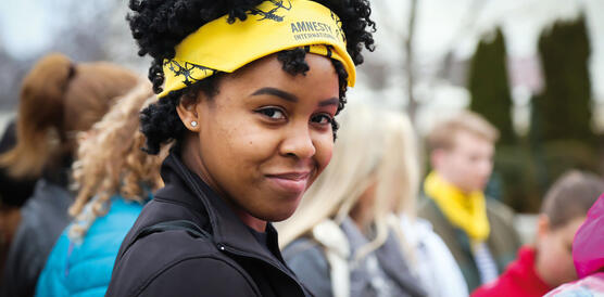 Porträtfoto einer Frau mit gelbem Amnesty-Haarband bei einer Kundgebung
