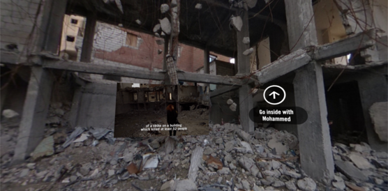 Der Ausschnitt aus einem 360-Grad-Video zeigt ein mehrstöckiges Haus liegt in Trümmern. In den Trümmern steht eine Amnesty Researcherin. 