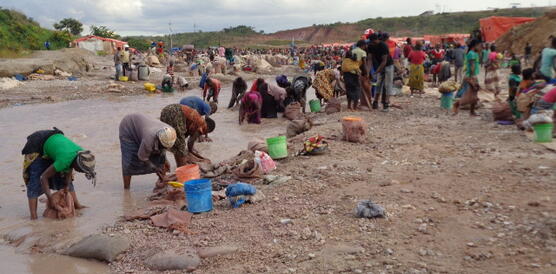 Frauen stehen gebückt in einem Fluss und waschen etwas aus