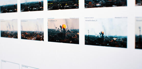 Fotos mit brennenden Häusern an einer Wand