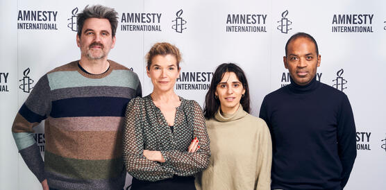 Zwei Männer und zwei Frauen stehen vor einer weißen Wand mit Amnesty-Logos