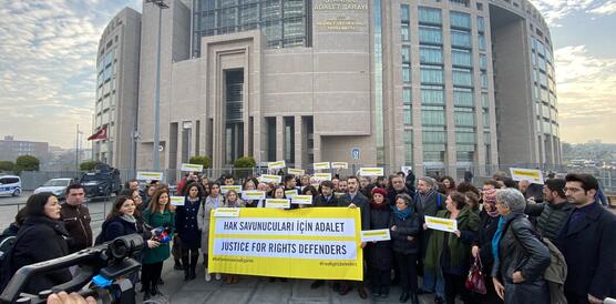 Viele Menschen stehen vor einem Gerichtsgebäude, sie halten Schilder in den Händen auf den steht "Gerechtigkeit für Menschenrechtsverteidiger"