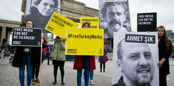Aktivistinnen von Amnesty stehen vor dem Brandenburger Tor und halten Plakate, mit denen sie Pressefreiheit in der Türkei fordern. 