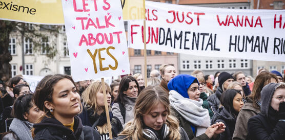 Mehrere Frauen demonstrieren, sie tragen Schilder mit der Aufschrift "lets talk about yes", manche applaudieren.