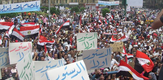 Der Patz ist gefüllt mit tausende Menschen, von denen viele Papptafeln mit Slogans in arabischer Schrift hochhalten oder die die ägyptische Fahne schwenken.