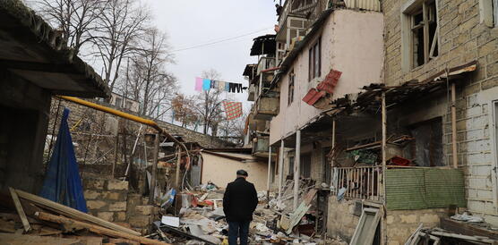 Ein Mann steht vor einem zerstörten Wohngebäude.