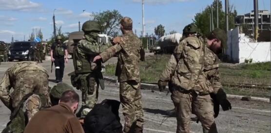 Bewaffnete russischen Soldaten durchsuchen auf einer Straße unbewaffente ukrainische Soldaten, die sich ergeben haben.