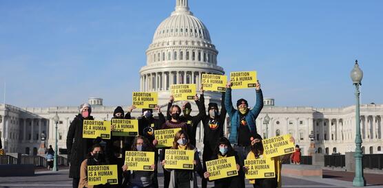 Das Bild zeigt eine ungefähr zwölfköpfige Gruppe an Demonstrierenden vor dem Kapitol in Washington, die jeweils Amnesty-Schilder mit der Aufschrift "Abortion is a human right" halten