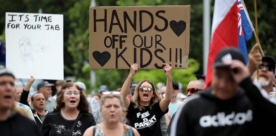 Demonstration von Menschen ohne Masken. Zentral hält eine Frau ein Plakat mit der Aufschrift "Hands of our kids".
