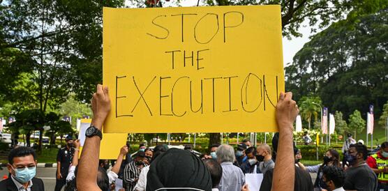 Das Bild zeigt einen Demonstrierenden mit einem Schild: "Stop the execution"