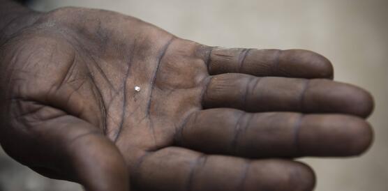 Das Bild zeigt eine Hand, in der ein sehr kleiner Diamant liegt