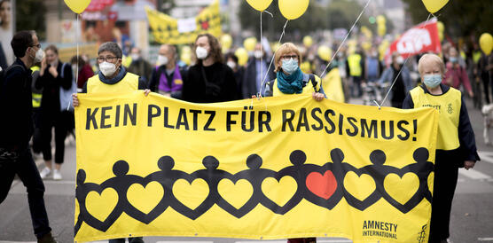 Das Bild zeigt mehrere Personen, die ein großes gelbes Banner tragen