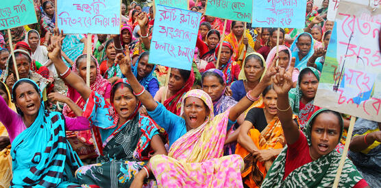 Das Bild zeigt mehrere Frauen, die auf dem Boden sitzen und Protestschilder halten.
