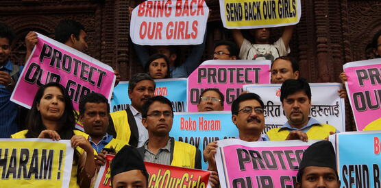 Personen stehen eng nebeneinander auf einer Treppe und halten Schilder und Plakate hoch, auf denen unter anderem steht "Bring back our girls".