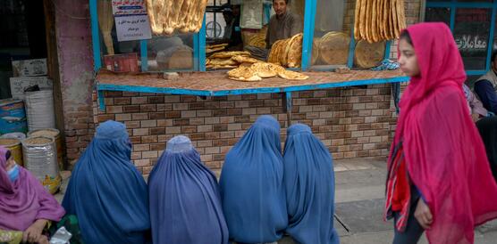 Das Bild zeigt mehrere Frauen in Burka, die vor einer Bäckerei sitzen 
