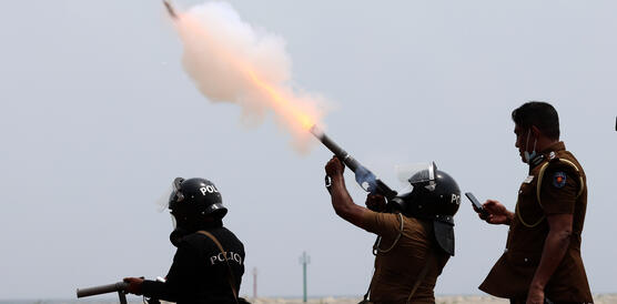 Das Bild zeigt, wie ein Polizist Tränengas in die Himmel schießt