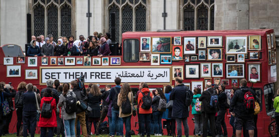 Das Foto zeigt, einen roten Doppeldecker-Bus vor einer Menschenmenge, auf dem viele eingerahmte Portraitbilder von verschiedenen Menschen zu sehen sind. Dazwischen steht der Schriftzug "Set them free".