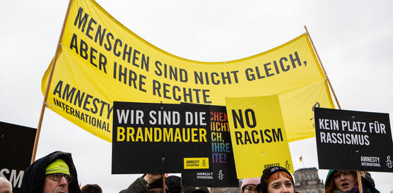 Das Bild zeigt Menschen mit Protestschildern