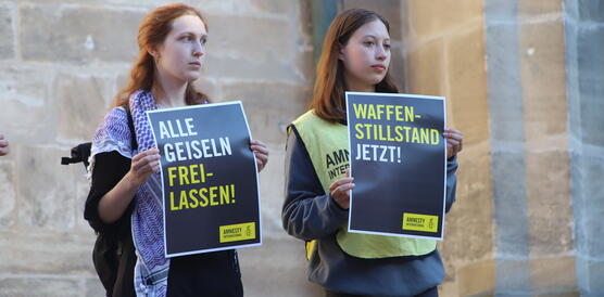 Das Bild zeigt mehrere Menschen mit Protestplakaten