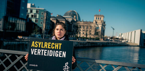 Das Bild zeigt eine Frau mit einem Protestplakat