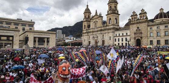 Eine bunte Menschenansammlung mit Plakaten und Masken auf einem großen Platz
