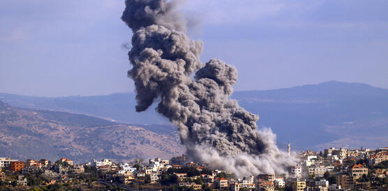 Rauchschwaden über einem kleinen Ort, im Hintergrund Berge
