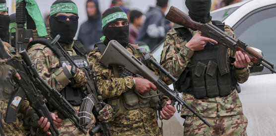 Das Foto zeigt drei mit Sturmgewehren bewaffnete maskierte Männer in Tarnuniform.