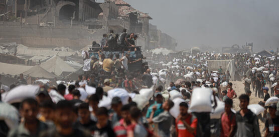 Hunderte Menschen drängen sich, manche Tragen Säcke auf den Schultern