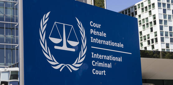 Ein großes blaues Schild vor einem Gebäude. Auf dem Schild steht: "International Criminal Court"