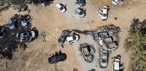 Luftaufnahme von mehr als einem Dutzend Autos auf einem Feldweg. Die meisten Türen stehen offen. Mehrere Fahrzeuge sind ausgebrannt.