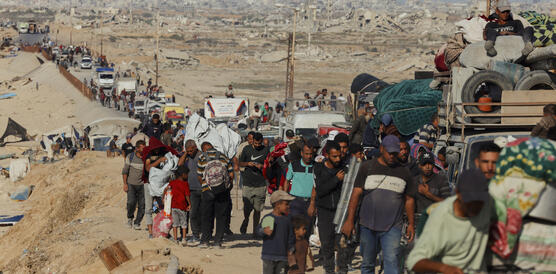 Zehntausende Menschen gehen mit schwerem Gepäck eine staubige Straße entlang