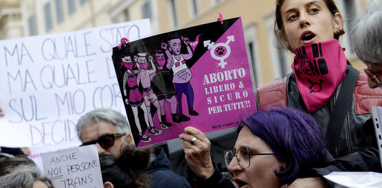 Das Foto zeigt demonstrierende Frauen, die während eines Protests Slogans rufen und Papptafeln hochhalten.
