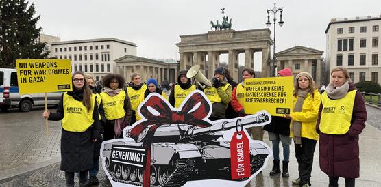 Mehrere Menschen mit gelben Leibchen mit der Aufschrift "Amnesty" und Protestplakaten