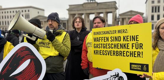 Mehrere Menschen protestieren mit Plakaten und Megaphon
