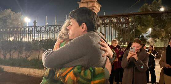 Zwei Personen, Sean Binder und seine Mutter, umarmen sich. Menschen, die dabei stehen, machen Fotos