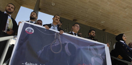 Mehrere Menschen halten ein großes Plakat, darauf zu sehen ein Strick und eine Person, die gehängt werden soll