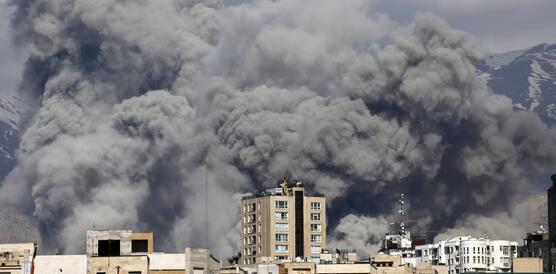 Riesige Rauchsäulen steigen zwischen mehrstöckigen Häusern empor. 