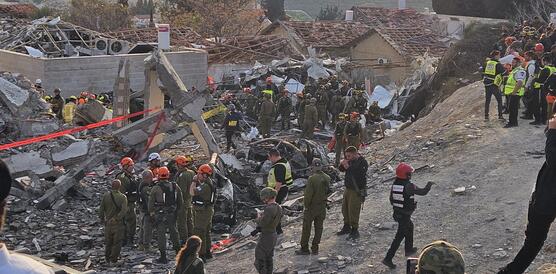 Das Foto zeigt uniformierte Rettungskräfte in den Trümmern eines zerstörten Gebäudes.