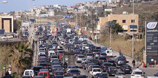 Das Foto zeigt eine mit mindestens 100 Autos vollgestopfte Straße am Rande einer Stadt.