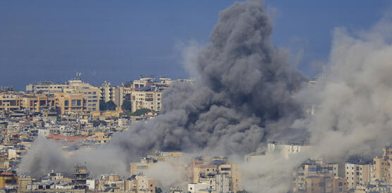 Eine große Rauchsäule steigt zwischen mehrstöckigen Gebäuden empor.