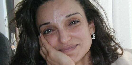 Porträtfoto von Saloua Ghrissa, die ihren Kopf mit ihrer rechten Hand stützt und in die Kamera lächelt.