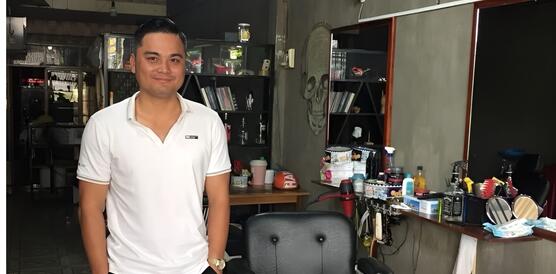 Das Foto zeigt Le Chi Thanh in einem Raum mit den Händen in den Hosentaschen. Er lächelt in die Kamera. Neben ihm steht ein Bürostuhl, hinter ihn ein Regal.