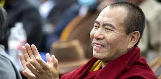 Seitenaufnahme von Choktrul Dorje Ten Rinpoche. Er lächelt und klatscht in die Hände.