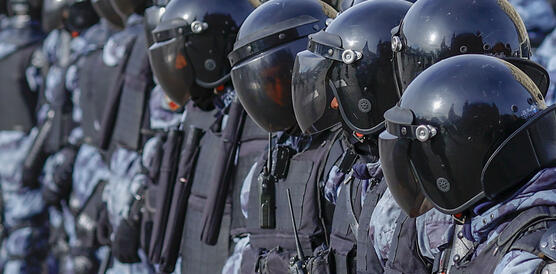 Das Foto zeigt uniformierte Polizisten in einer Reihe stehend. Sie tragen Helme mit verdunkelten Visiren, wodurch ihre Gesichter nicht zu erkennen sind.