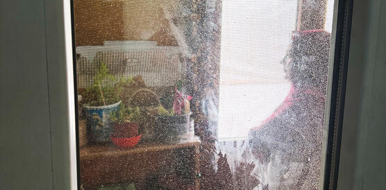 Eine Frau sitzt in der Küche eines Wohncontainers, sie trägt Kopftuch.
